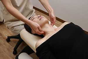 女性整体師が女性利用者に対して、首まわりをやさしく整える整体施術を行っている様子