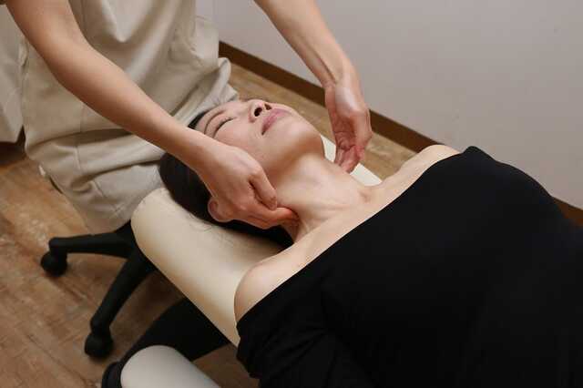 女性整体師が女性利用者に対して、首まわりをやさしく整える整体施術を行っている様子