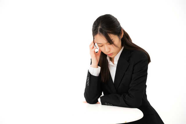 頭をおさえて俯く女性