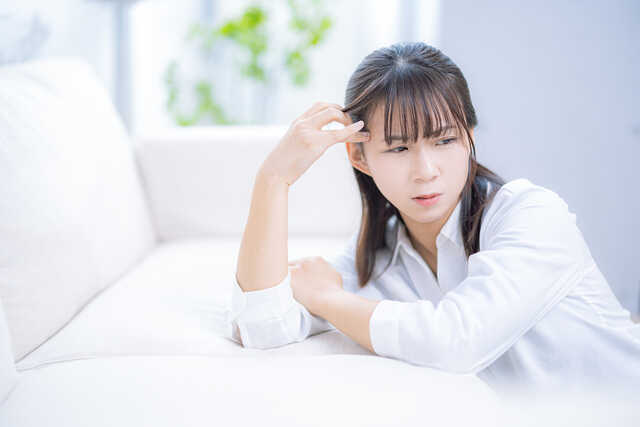 頭痛でソファにもたれる女性